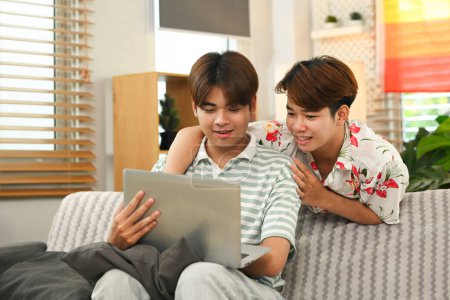 Photo for Happy gay couple watching movie on laptop in living room. LGBTQ, leisure and lifestyle concept. - Royalty Free Image