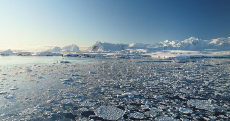 Foto de Paisaje ártico en día soleado, montañas cubiertas de nieve y océano de agua helada. Paisaje invernal antártico, problema de calentamiento global. Tierra blanca del desierto de nieve y hielo. Vuelo aéreo con drones sobre la naturaleza salvaje - Imagen libre de derechos