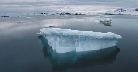 Dramatic melted iceberg from crashed glacier drift Antarctica ocean. Majestic winter Antarctic landscape. Ecology, melting ice, climate change, global warming concept. Aerial view drone panoramic shot