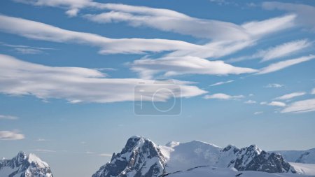 Paisaje con montañas de nieve en día nublado en la Antártida a la vista aérea. Helados de fiordo congelados y montajes fríos y nevados. Naturaleza afectada por el cambio climático y el calentamiento global