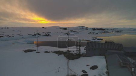 Coucher De Soleil Sur Vernadsky Arctic Station Vue Aérienne. Jour d'hiver Ciel en Antarctique Paysage de montagne. La base scientifique polaire explore le changement climatique mondial Drone Footage tourné en 4K UHD
