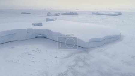 Tabulaire Iceberg coincé dans l'océan gelé Vue Aérienne. Snow Covered Antarctica Lagoon Nature Seascape at Peninsula Shore. Hiver Paisible Froid Islande Mer Floe Top Drone Shot Footage 4K UHD
