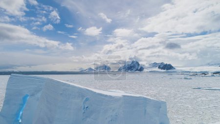 Foto de Vuelo aéreo sobre la Antártida Iceberg, Océano. Paisaje blanco. Increíble tiro de dron de hielo congelado océano. Cielo nublado y montañas cubiertas de nieve soleada Fondo. Paisaje de invierno en el Polo Sur. Filmación 4k
. - Imagen libre de derechos