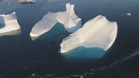 Iceberg Melt in Clear Ocean Drone Top Down View. Huge Snow Ice Float in Sea, Global Climate Change Concept Pan Left Flight. South Pole Glacier Landscape. Footage Shot in 4K UHD