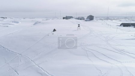 Mann fährt auf Oldtimer-Motorschlitten. Antarktisflug aus der Luft. Mann mit Ski-Doo neben der Vernadsky-Station. Übersicht Drohnenaufnahmen der Schnee-Polarlandschaft. Wildnis. Exotisches Reisen. 4k Filmmaterial.