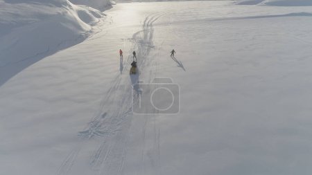 Ski-doo Pull Skiing on Snow Surface Aerial View. Drone Flight Tracking Shot Vintage Snowmobile Ride Play at Antarctica Frozen Landscape. Extreme Adrenaline Driving in Arctic Overview Footage 4K UHD