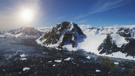 Sunset Over Lemaire Channel. Antarctica Aerial Flight Over Polar Ocean, Snow Covered Mountains. Drone Overview Shot Of Polar Bay. Bright Sun Over Mighty Mounts, Ice Cold Ocean. 4k Footage.