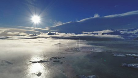 Foto de 4k Paisaje Antártico. Avión no tripulado de visión aérea. Huella solar de sol polar brillante blanco sobre el océano cubierto por niebla de luz. Superficie cubierta de hielo y nieve del continente antártico. Panorámica general
. - Imagen libre de derechos