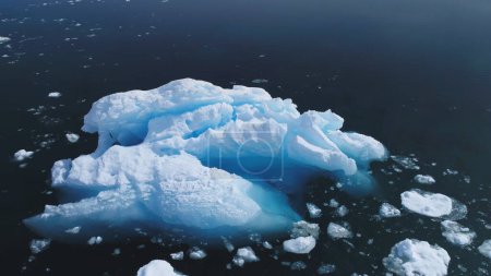 Aerial Flight Over Huge Iceberg In Antarctica Ocean. Drone View From Above Ice Mount Floating In Clear Water. Winter Polar Ocean Scape. Harsh Environment. Permafrost. 4k Footage.