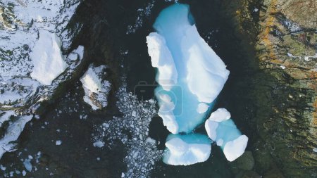 Iceberg coincé dans la péninsule Ocean Shore Vue Aérienne. Grande pièce de glace turquoise qui fond sur la côte antarctique. Hiver Belle Froid Islande Mer Floe Top Down Drone Shot Footage 4K UHD
