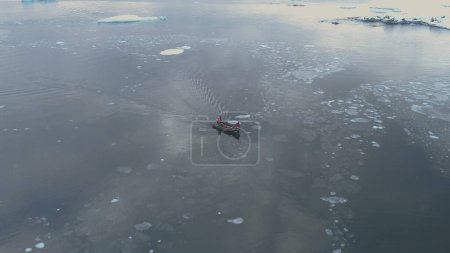 Zodiac Boat Sail Brash Ice Tracking Aerial View. Flight Above Transport Rubber Boat Float in Extreme Winter Cold Antarctic Water. South Pole Ocean Seascape Drone Footage Shot in 4K UHD
