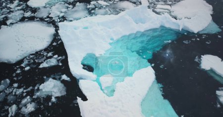 Melting iceberg underwater ice in Antarctica. Crashed glacier pieces floating icy cold ocean. Arctic scene. Ecology, melting ice, climate change and global warming concept. Aerial top view drone shot