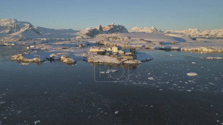 Aerial drone view flight. Vernadsky Base, ocean, mountains. Fast hyperlapse shot. The station settlement on the Antarctica continent surrounded snow covered mountains and ice ocean. Harsh conditions