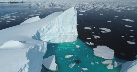 Huge snow glacier melting in South Pole ocean. Crashed ice floating blue water. High icebergs in Antarctica. Environment ecological issue of global warming and climate change. Aerial drone panorama