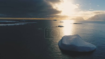 Foto de Iceberg al atardecer sobre la Antártida. Vista aérea frontal. Reflexión solar sobre el agua del océano en el verano antártico. Hermoso paisaje de hielo, cielo y océano. Avión no tripulado vuelo adelante - Imagen libre de derechos