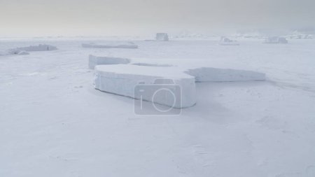 Téléchargez les photos : Vue aérienne du champ de glace océanique gelé coincé tabulaire. Snow Covered Antarctica Coast Nature Seascape at Peninsula. Hiver Belle Froid Islande Floe Top Drone - en image libre de droit