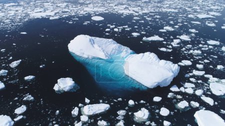 Aerial Flight Over Iceberg Among Antarctica Ocean. Climate Change in Winter Ocean Scape. Drone Shot Of Huge Ice Glacier, Snow Pieces Floating In Clear Ocean Water. Antarctic Polar Scene. 4k Footage.