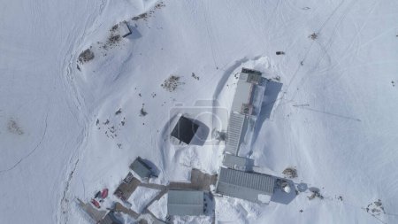 Vuelo aéreo con vista a drones. Base Vernadsky, océano, montañas. Rápido. El asentamiento de la estación en el continente Antártico rodeó montañas cubiertas de nieve y océano de hielo. Condiciones duras.