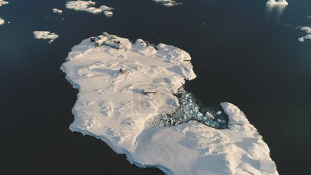 Hubschrauberlandung von oben über der antarktischen Polarstation - dem Vernadsky Base. Wasseroberfläche des Ozeans. Schneebedeckte Südpol-Siedlung. Naturlandschaft aus der Luft. Flucht