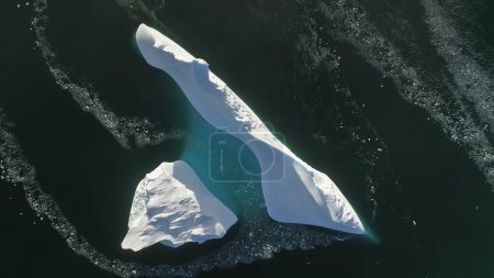 Antártida iceberg vuelo aéreo vista avión no tripulado. Rápido de arriba hacia abajo. Descripción general de la única montaña de hielo blanco como la nieve, entre el agua polar del océano de invierno. Belleza de la naturaleza virgen salvaje. .
