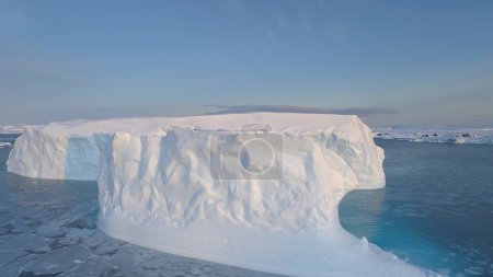 Aerial of close-up white and blue big iceberg. Antarctica panoramic drone flight view. Ice among polar ocean. Iceberg floating around frozen water. Permafrost. Antarctic continent.