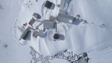 Aerial drone view flight. Vernadsky Base, ocean, mountains. Fast. The station settlement on the Antarctica continent surrounded snow covered mountains and ice ocean. Harsh conditions.