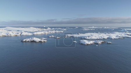Foto de Volando sobre la superficie del océano Antártico y las islas cubiertas de nieve. Antártida icebergs de aguas abiertas panorama del paisaje. Vista aérea del cambio climático en la costa natural. Drone flightin - Imagen libre de derechos