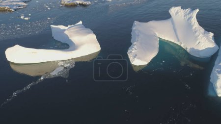 Iceberg Melt in Clear Ocean Drone Top Down View. Huge Snow Ice Float in Sea, Global Climate Change Concept Pan Left Flight. South Pole Glacier Landscape.