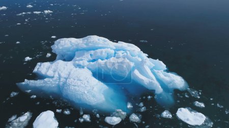 Luftflug über den riesigen Eisberg im antarktischen Ozean. Drohnenblick über dem Eisberg, der im klaren Wasser schwimmt. Winter Polar Ocean Scape. Harsche Umweltbedingungen. Permafrost.