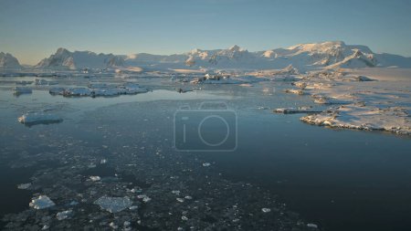 Antarctica aerial view drone flight, over ocean to the mountains. Fast overview the polar ocean, mighty mountains and snow covered Antarctic continent. flying over ice water surface.