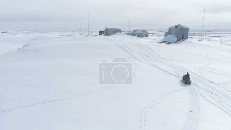 Hombre montando en moto de nieve Vintage. Vuelo Aéreo Antártida. Hombre usando Ski-doo junto a la estación Vernadsky. Descripción general Drone Of Snow Polar Landscape. Silvestre. Viaje exótico.