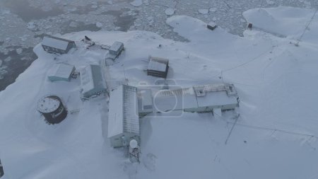 Aerial drone view flight. Vernadsky Base, ocean, mountains. Fast. The station settlement on the Antarctica continent surrounded snow covered mountains and ice ocean. Harsh conditions.