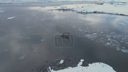 Foto de Zodiac Boat Sail Brash Ice Tracking Vista aérea. Vuelo por encima del transporte Flotador de goma en invierno extremo Agua fría de la Antártida. Polo Sur Océano Paisaje marino Drone - Imagen libre de derechos