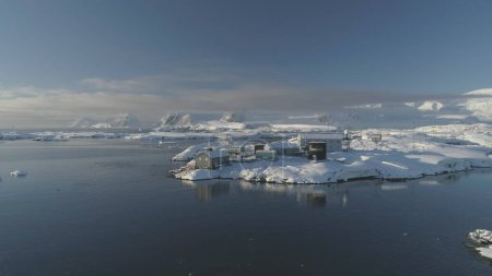 Slow-motion aerial flight of Antarctic Science Station - Vernadsky Base. Drone View Ocean Coast Open Water Surface. South Pole Settlement Landscape Aerial Slow Speed Flight.