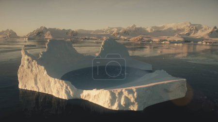 Eisbergbad. antarctica Drohnenflug aus der Luft. Zeitlupe fliegt über den großen Eisberg mit Wasserbecken im Polarmeer neben den schneebedeckten Bergen des antarktischen Kontinents. 4k Filmmaterial.
