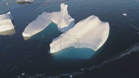 Iceberg Melt in Clear Ocean Drone Top Down View. Huge Snow Ice Float in Sea, Global Climate Change Concept Pan Left Flight. South Pole Glacier Landscape.