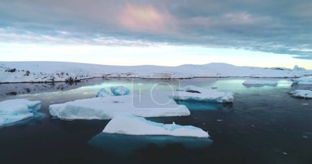 Gruppe von Eisbergen schwimmt im Sonnenuntergang auf der Oberfläche des arktischen Ozeans, kaltes Wasser unter farbenfrohen Himmelsspiegelungen. Natürliche Schönheit der schmelzenden Gletscher. Ökologie, schmelzendes Eis, Klimawandel und globale Erwärmung