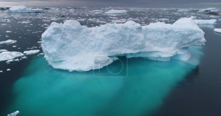 Massive iceberg floating in Antarctica ocean. Snow covered blue ice melting underwater. Ecology, climate change and global warming concept. Antarctica travel and exploration. Aerial drone panorama