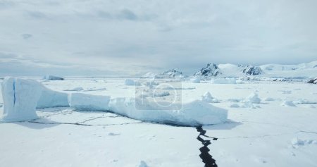 Foto de Colosal iceberg del glaciar estrellado que se eleva en el océano congelado. Tierra blanca del desierto de nieve y hielo. Cordillera en el fondo. Antártida viajes y exploración. Descubre la belleza del Polo Sur - Imagen libre de derechos