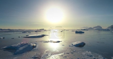 Strahlende Sonne über der arktisch gefrorenen polaren Meereslandschaft. Eisschollen bedecken kaltes Wasser im Sonnenuntergang. Atemberaubende Harmonie unberührte Natur. Majestätischer Winter in der Antarktis. Reisen, erkunden. Tieffliegerdrohne abgeschossen