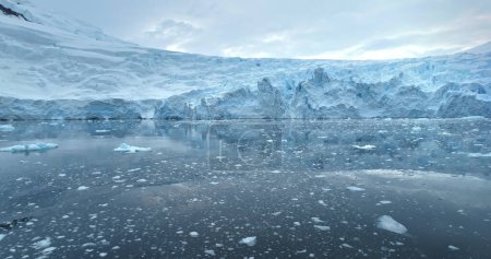 Massiver blauer Gletscher, der in antarktischen Gewässern thront. Schneebedeckte Eisbergreflexion treibt polare Eismeere. Ökologie, schmelzendes Eis, Klimawandel und globale Erwärmung. Drohnenflug im Tiefflug
