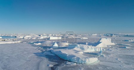 Winter Arctic landscape aerial panorama. Icebergs in frozen ice ocean under bright blue sky. Desert white land of snow and ice, South Pole. Pristine Antarctic scene. Antarctica travel and exploration