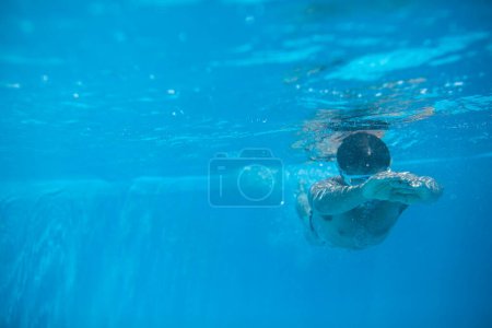 Foto de Nadador masculino nadando en una piscina al aire libre - manteniéndose en forma - Imagen libre de derechos