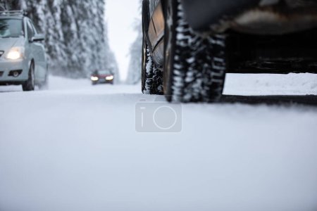 Foto de Coche en una carretera nevada de invierno en medio de los bosques, utilizando sus capacidades de tracción a las cuatro ruedas para atravesar la nieve - Imagen libre de derechos