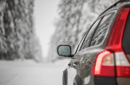 Téléchargez les photos : Voiture sur une route enneigée d'hiver au milieu des forêts en utilisant ses capacités de quatre roues motrices pour traverser la neige - en image libre de droit