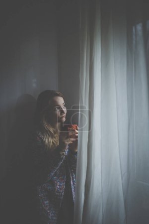 Téléchargez les photos : Froid, déprimé, jeune femme à la maison se sentant triste, seule, anxieuse (image couleur tonique) - en image libre de droit