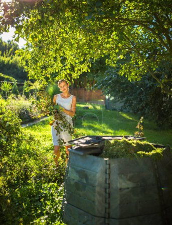 Photo for Pretty, young woman gardening in her garden, cutting branches, preparing the orchard for the winter - Royalty Free Image