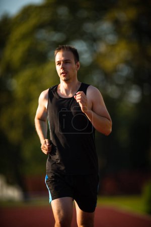 Photo for Handsome young runner jogging outdoors on a lovely summer evening - Royalty Free Image