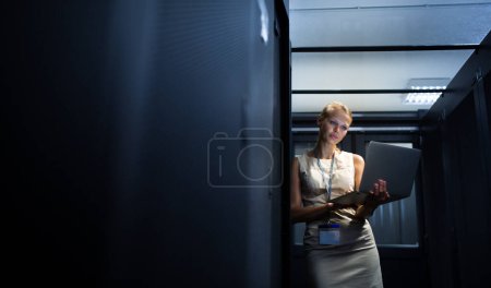 Foto de Ingeniero de TI de pie antes de trabajar en el rack del servidor haciendo revisiones y diagnósticos de mantenimiento rutinarios usando computadora portátil - Imagen libre de derechos