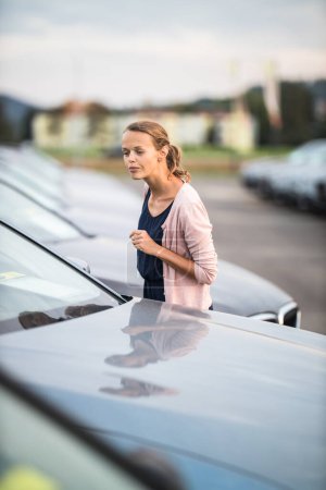 Photo for Pretty, young woman looking at cars, picking the model she would buy. - Royalty Free Image